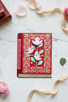 Red Book Pink Florals card flat on white marble with vintage books and pink florals