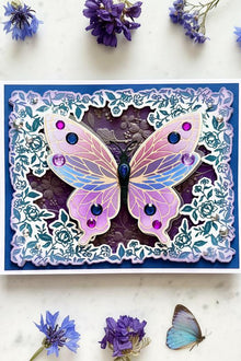 Flutter Wing Butterfly card flat on white marble with violet and blue wildflowers and butterfly specimens